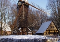 Eine alte Mühle und ein Fachwerkhaus, die von Schnee bedeckt sind. 