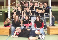 Eine Gruppe von Personen posiert in einer Turnhalle vor und hinter einem Netz. 